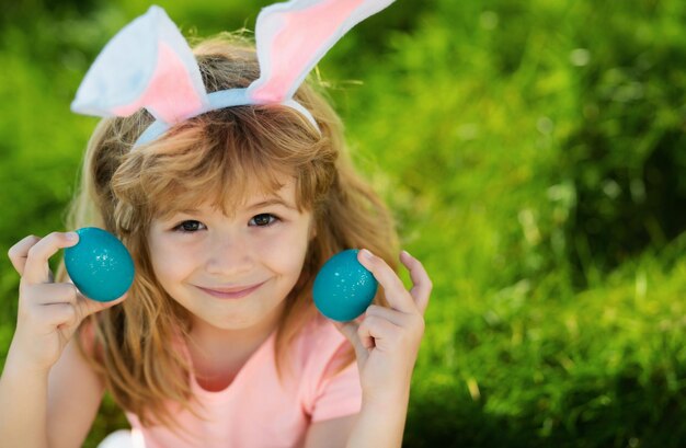 Foto bambino coniglio di pasqua bambini a caccia di uova di pasqua ragazzo con uova di pasqua e orecchie di coniglio nel cortile posteriore vacanze di primavera