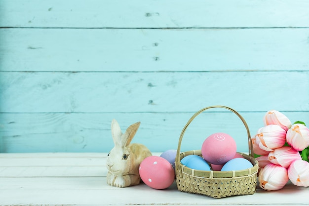 Bunny and easter eggs with tulips on table at home