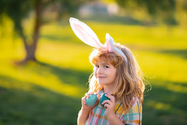 Bunny kind jongen gezicht kinderen in konijnenoren op paaseieren zoeken in tuin kinderen met kleurrijke eieren in ...