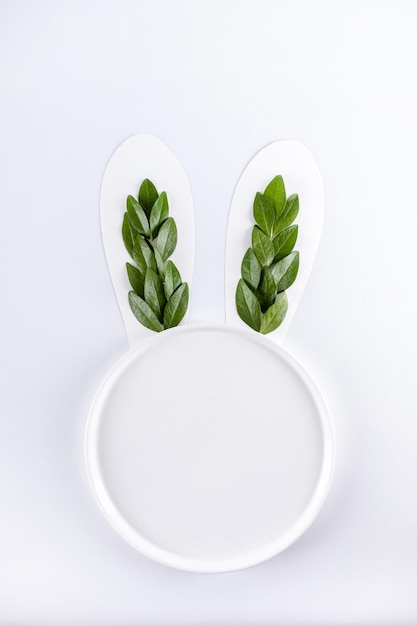 Кроличьи уши из натуральных зеленых листьев на белом фоне с круговым пространством для копирования Плоская планировка Пасха минимальная концепция