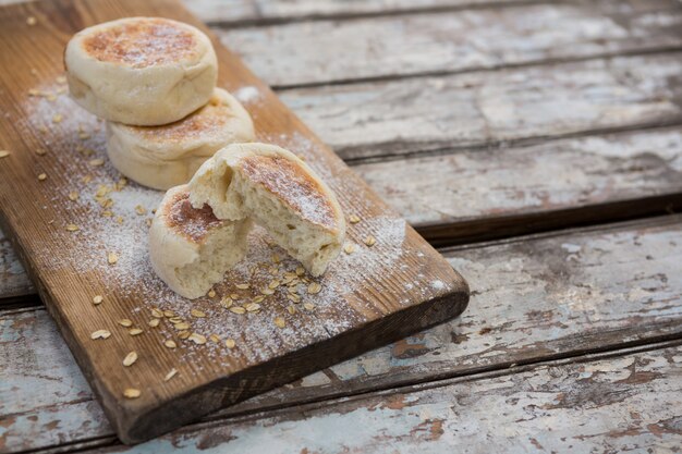 Buns with wheat flour on wooden plank