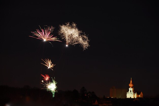 Buntes grosses feuerwerk in der nacht zu silvester mit einer kirche rechts