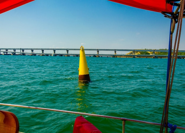 A buoy in the sea near the bridge on a summer day.