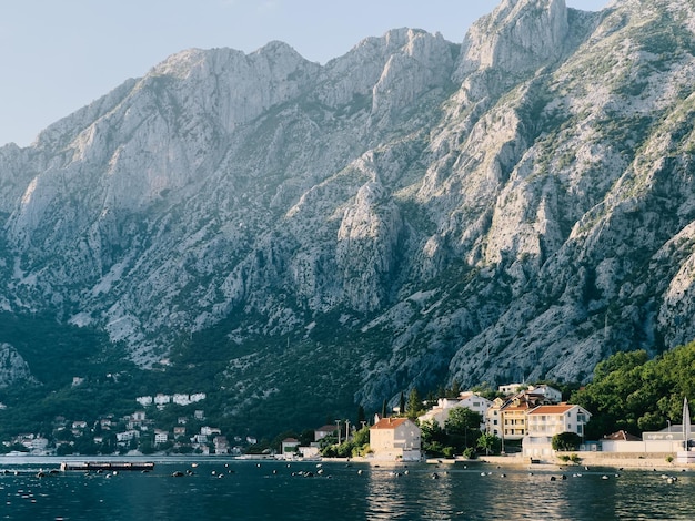 Buoys float off the coast of an old town with stone houses and red roofs