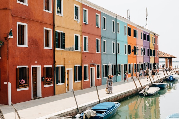 Burano, Venetië, Italië - 2 juli 2018: Panoramisch uitzicht op felgekleurde huizen en waterkanaal met boten in Burano, het is een eiland in de lagune van Venetië. Mensen lopen en rusten op straat