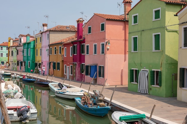 Burano, venezia, italia - 2 luglio 2018: vista panoramica di case dai colori vivaci e canale d'acqua con barche a burano, è un'isola della laguna veneziana. la gente cammina e riposa per strada