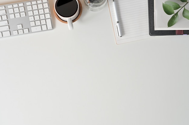 Bureau met bovenaanzicht kopie ruimte toetsenbord computer, koffie, notebookpapier en kantoorbenodigdheden op het bureau.