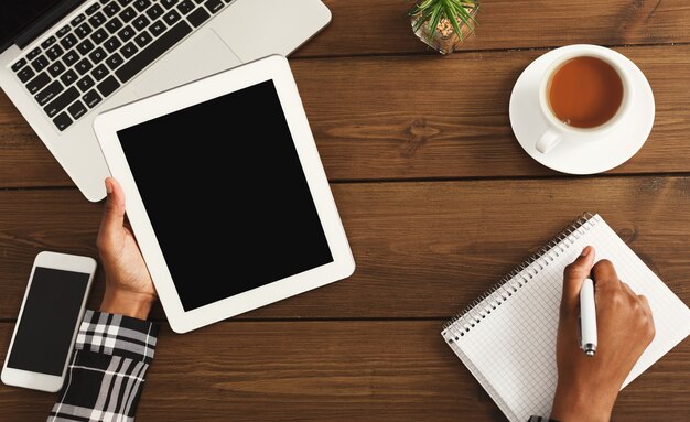 Bureau met laptop, smartphone, tablet, kopje koffie en schrijfblok