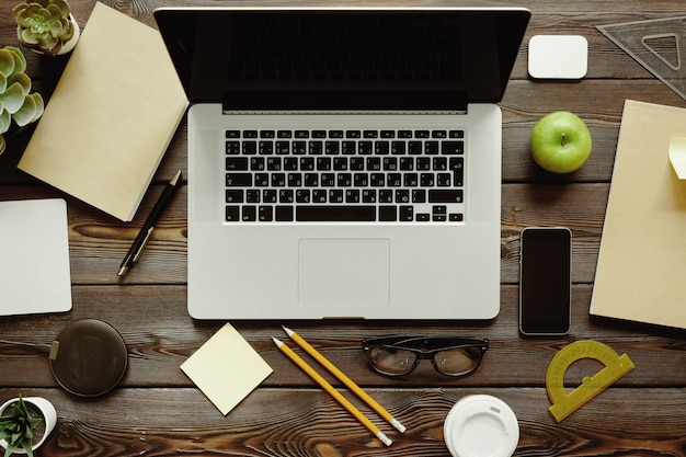 Bureau met laptopcomputer, leveringen en groene appel, bovenaanzicht