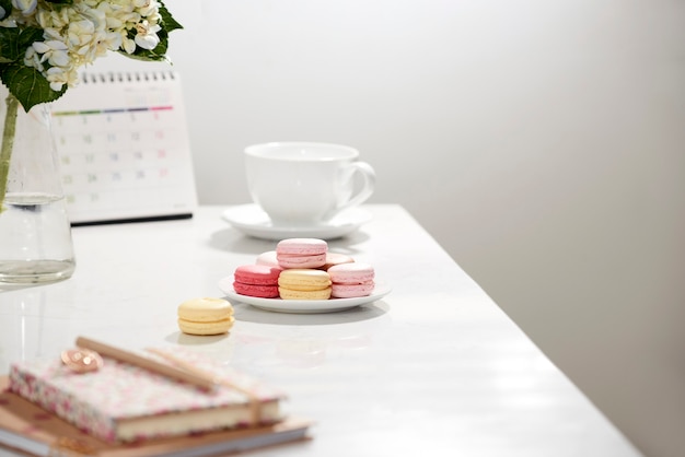 Bureau tafel bureau. vrouwelijk bureauwerkruimteframe met kalender, agenda, hortensiaboeket, macaron en koffie op wit