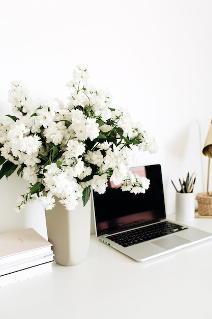 Bureau-werkruimte met bloemenboeket, laptop en tafellamp