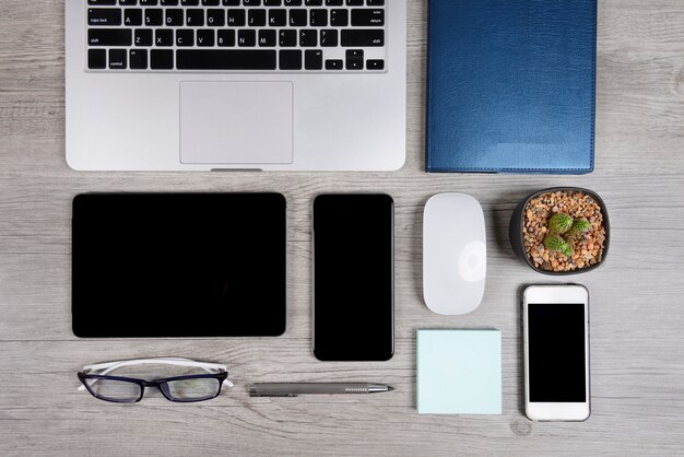 Bureaulijst met laptop computer, notitieboekje, digitale tablet, en smartphone op hout backgr