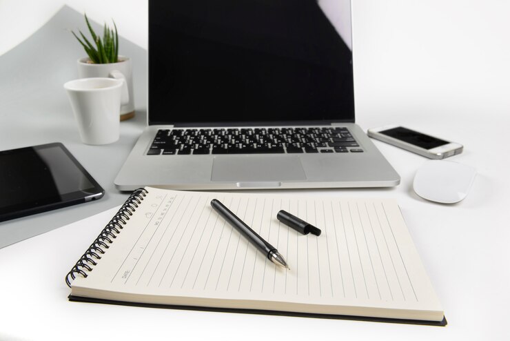 Bureaulijst met laptop computer, notitieboekje, digitale tablet en smartphone op twee toonbedelaars