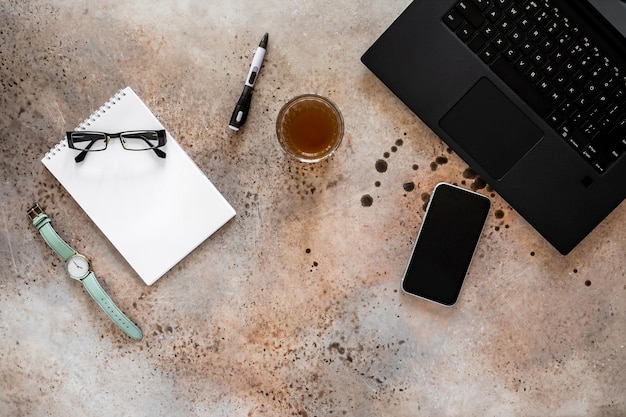 Bureautafel met laptop notitieblok pen smartphone bril en glas koffie bovenaanzicht mockup kopieerruimte