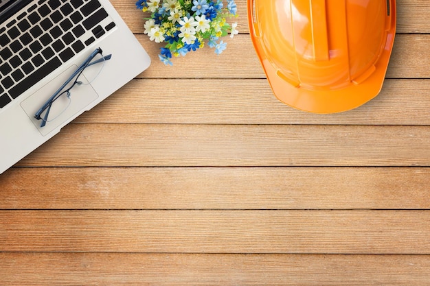 Bureautafel met oranje veiligheidshelmlaptop computerbril op houten tafel