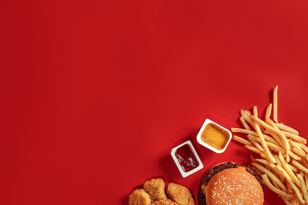 Фото Гамбургер и чипсы, гамбургер и картофель фри в красной бумажной коробке фаст-фуд на красном фоне