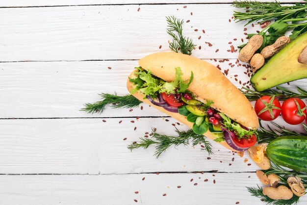 Burger avocado sandwich cherry tomatoes and lettuce leaves On a wooden background Top view Copy space