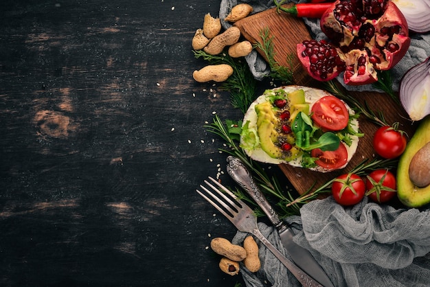 Burger avocado sandwich cherry tomatoes and lettuce leaves On a wooden background Top view Copy space