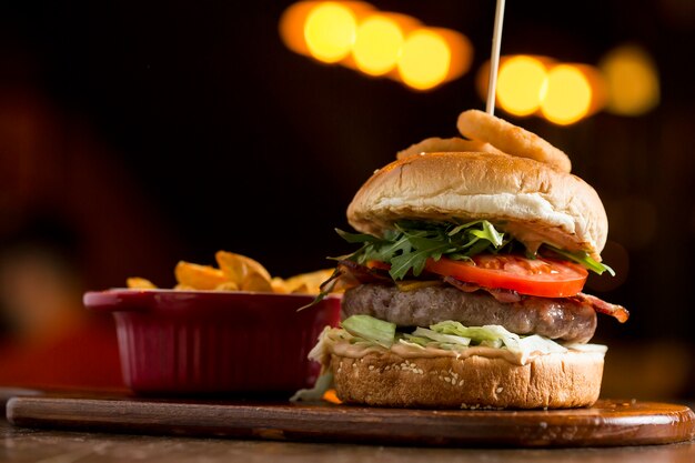 Burger of beef meat with melted chedar cheese, bacon,tomato, rocket salad with fried onion and spicy fries