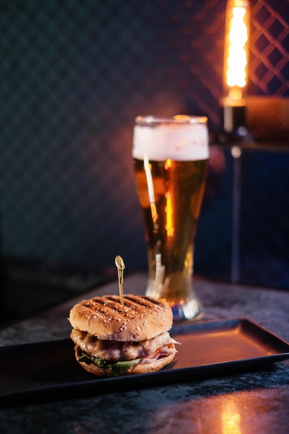 Burger and beer set Drink and snack on the red bar Fast food A burger with beef and a glass of beer