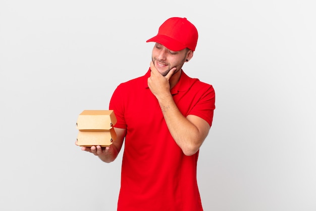 Burger bezorgt man glimlachend met een gelukkige, zelfverzekerde uitdrukking met de hand op de kin