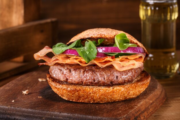 Burger close up on a cutting board on wooden background.