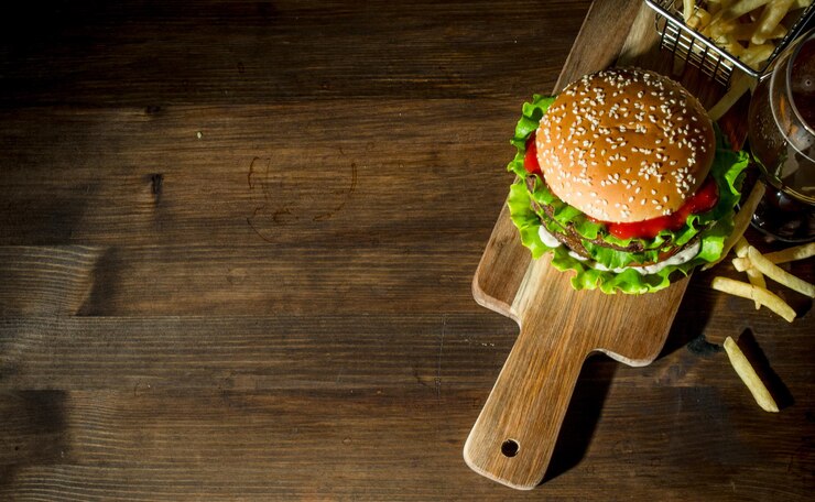 まな板の上のハンバーガーとビールとフライドポテト