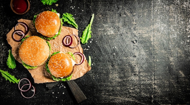 Burger on a cutting board with onion rings tomato sauce and lettuce