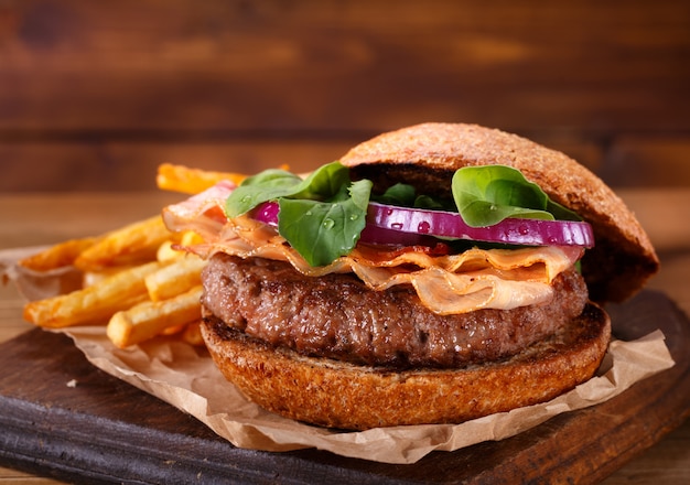 L'hamburger e le patate fritte si chiudono su su fondo di legno.