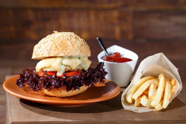 Burger and french fries on the wooden table.