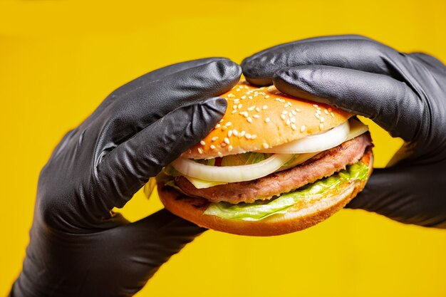 burger in hands in feathers on a yellow