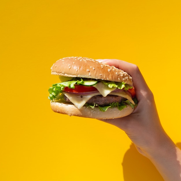 Hamburger tenuto di fronte a sfondo giallo