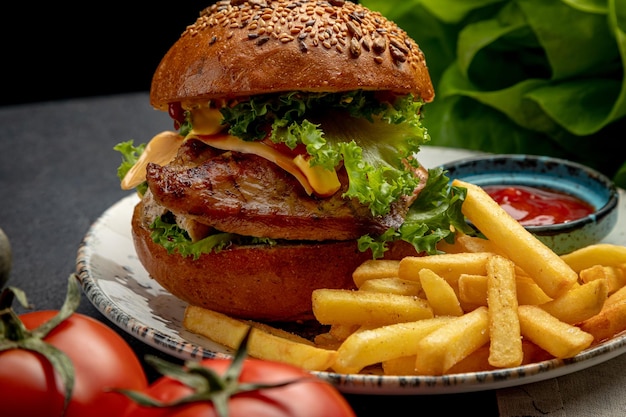 Burger met steak sla en kaas geserveerd met frietjes en saus op een donkere achtergrond