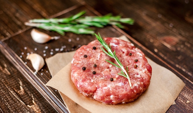 burger patties with seasoning on wood background