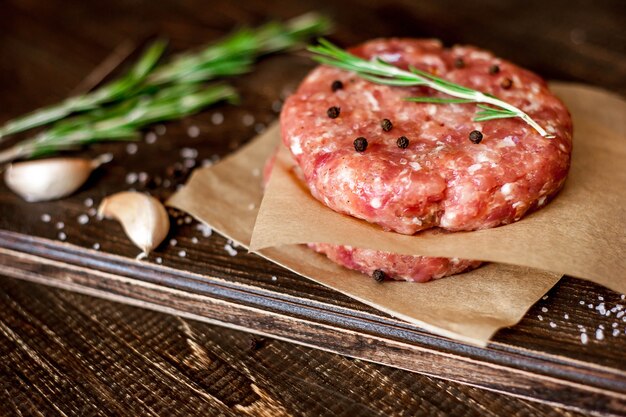 burger patties with seasoning on wood background