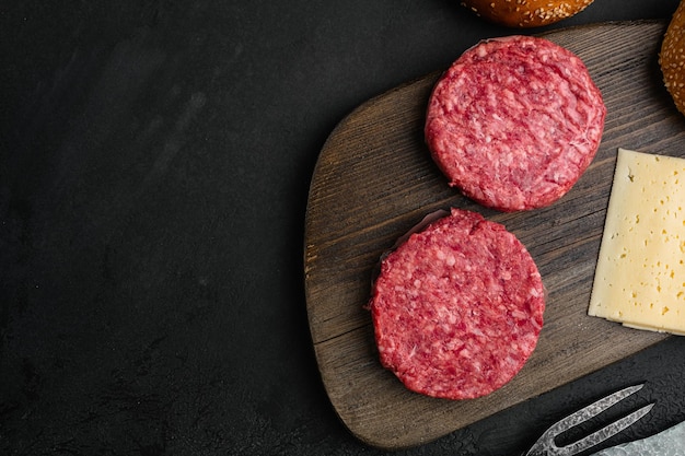 Hamburger patty carne di manzo macinata su sfondo nero tavolo in pietra scura vista dall'alto piatto con spazio per la copia del testo