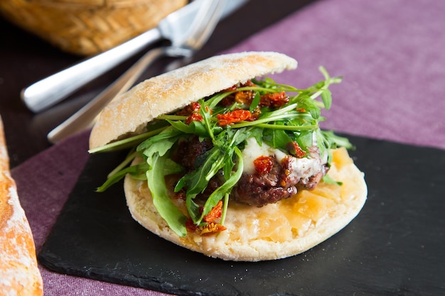 A burger with arugula on a black plate