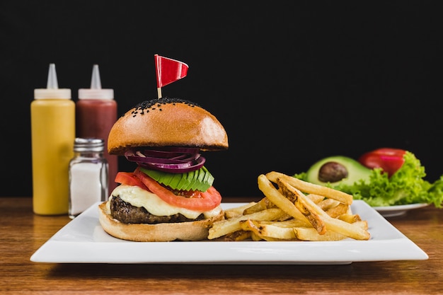 Burger with avocado, tomato, onion, cheese and french fries