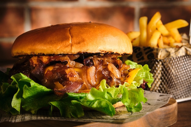 Hamburger con carne di manzo e cipolle caramellate su una tavola di legno. cheeseburger con cipolla e manzo. hamburger fatto in casa delizioso succoso.