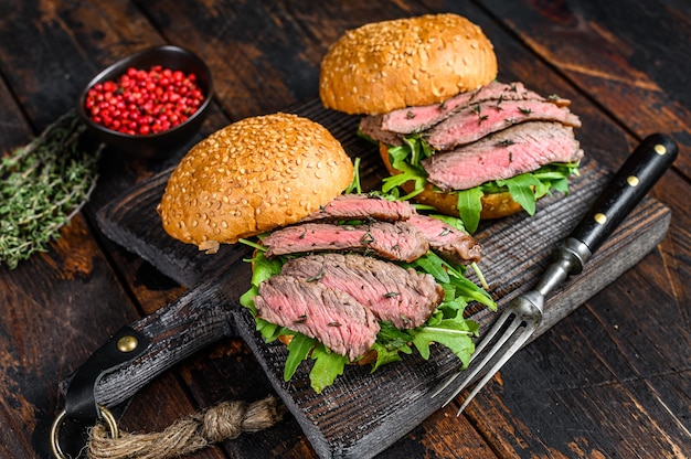 Burger with beef steak slices, arugula and spinach