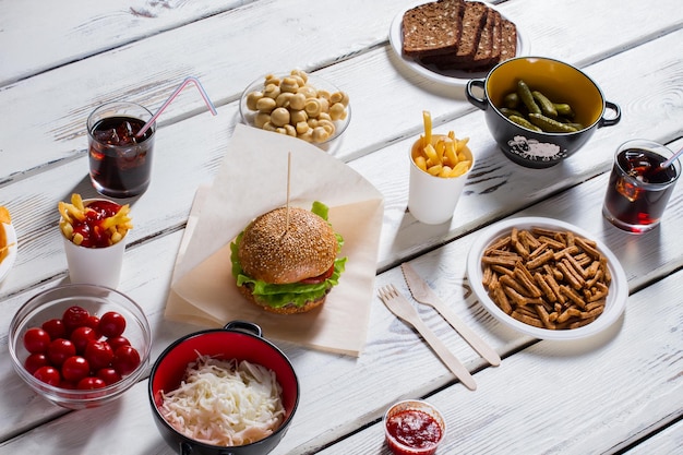 Hamburger con pane e cracker pomodori cola e hamburger cibo sul tavolo da cucina bianco siediti e aiutati