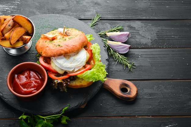 Burger with camembert cheese and meat French fries and ketchup Top view free space for your text Rustic style