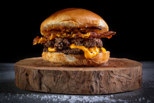 Burger with cheddar cheese on wooden plate