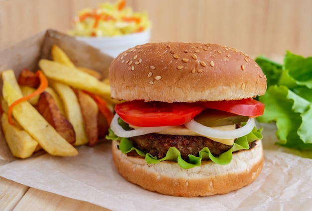 Burger with cheese, tomatoes and juicy burgers. Cabbage salad. French fries.