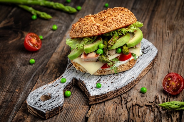 burger with chicken fillet, asparagus, avocado, tomatoes, peas, cheese and tartar