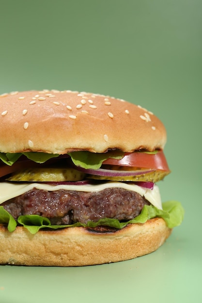 Burger with delicious patty on green background closeup