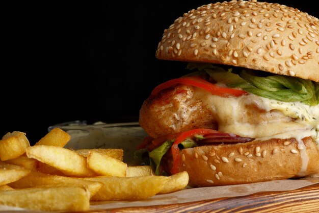 黒の背景にフライド ポテトとハンバーガー。バーガークローズアップ