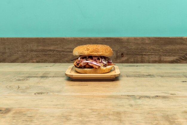 Burger with grilled meat and raw red onion on wooden table