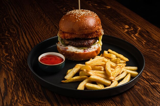 A burger with meat patty and fried or grilled cheese served with tomato ketchup sauce and french fries