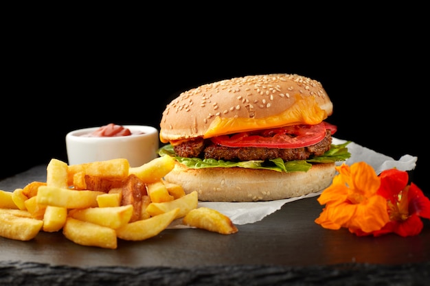 Burger with meat and potatoes on black slate